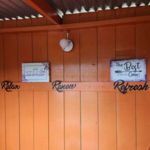 bright orange wooden wall with black cursive wording that says Relax, Renew, and Refresh