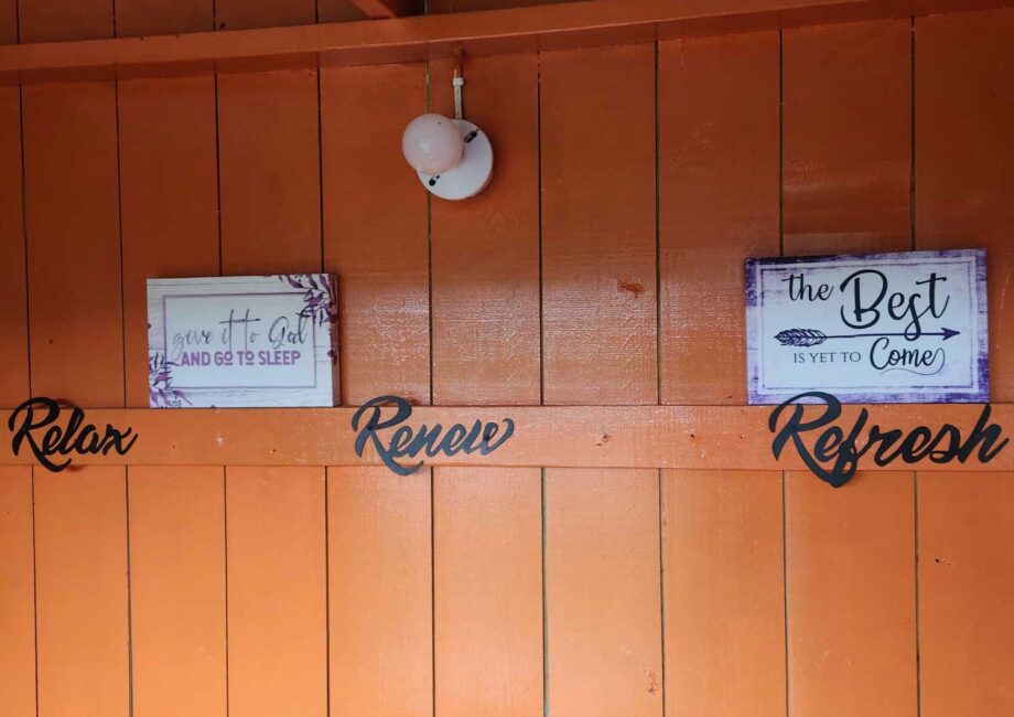 bright orange wooden wall with black cursive wording that says Relax, Renew, and Refresh
