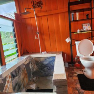 private bathrooms in one of the tiny homes that has a toilet and a mosaic tile shower with a bright orange wooden walls