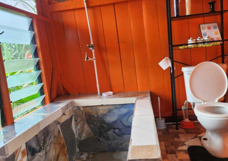 private bathrooms in one of the tiny homes that has a toilet and a mosaic tile shower with a bright orange wooden walls