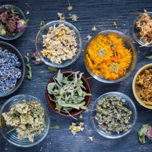 dried herbs in bowls on a dark wooden background